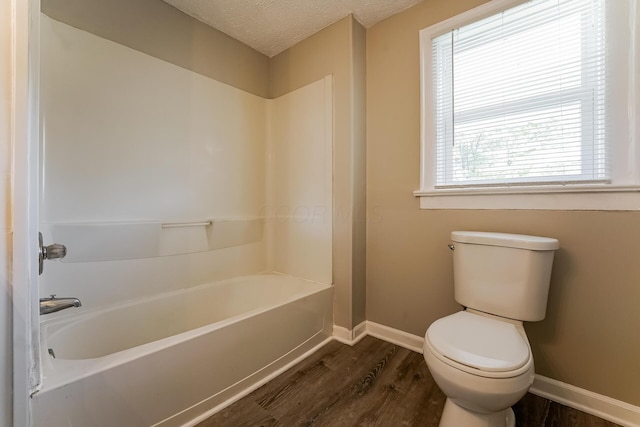 bathroom with wood-type flooring, toilet, a textured ceiling, and a washtub