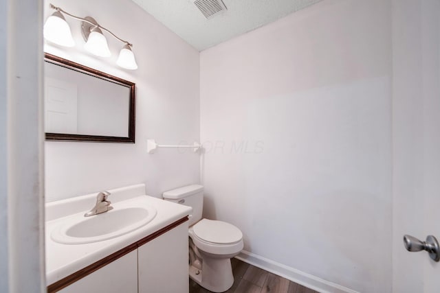 bathroom with vanity, wood-type flooring, a textured ceiling, and toilet