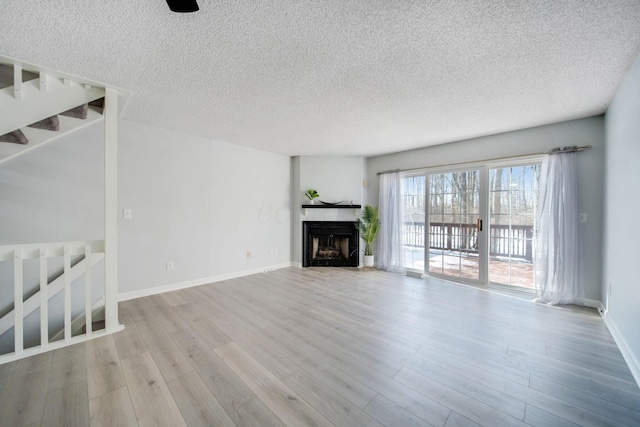 unfurnished living room with light hardwood / wood-style floors and a textured ceiling