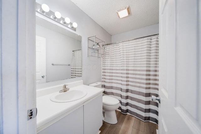 bathroom featuring vanity, hardwood / wood-style flooring, toilet, and a textured ceiling