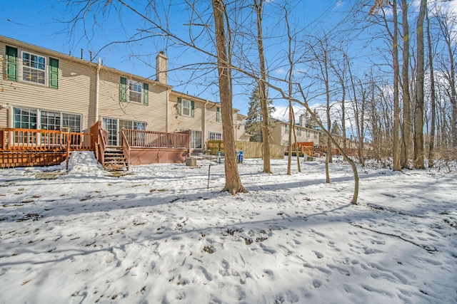 snow covered back of property featuring a wooden deck