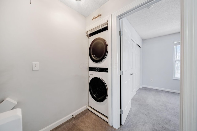 laundry area featuring stacked washer and dryer, light colored carpet, and a textured ceiling