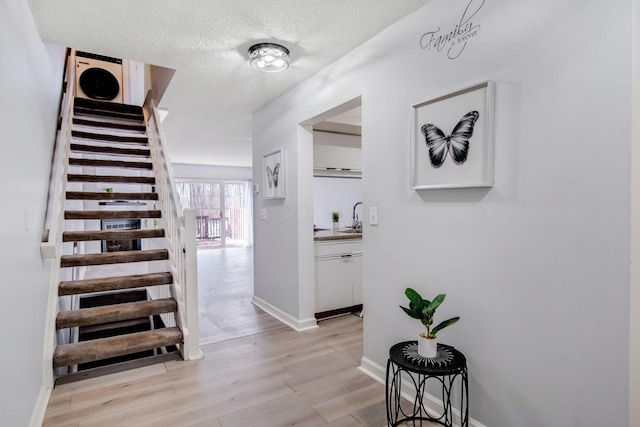 staircase featuring sink, wood-type flooring, and a textured ceiling