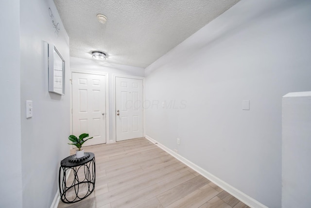 hallway with light hardwood / wood-style flooring and a textured ceiling