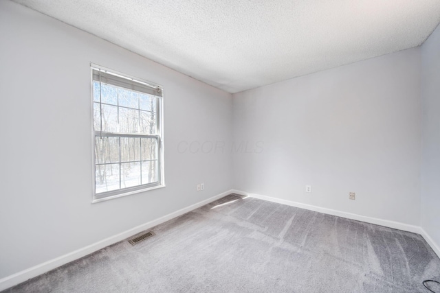 carpeted empty room featuring a textured ceiling