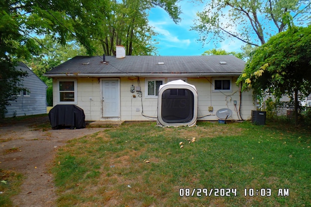 back of property featuring central air condition unit and a lawn