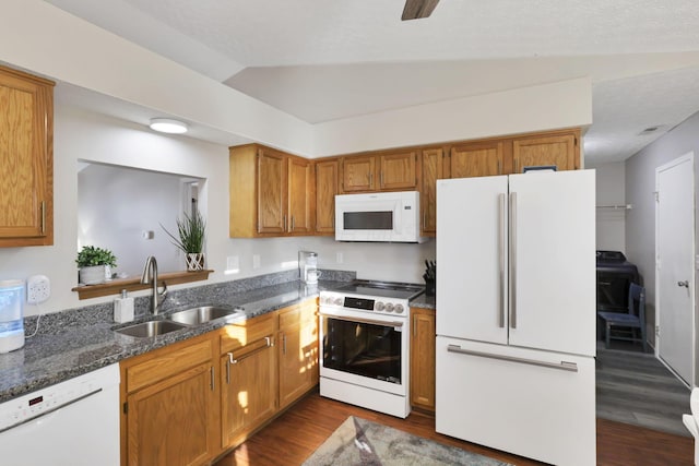 kitchen with lofted ceiling, sink, dark hardwood / wood-style floors, white appliances, and dark stone counters