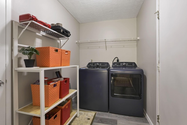 laundry area with wood-type flooring, washer and dryer, and a textured ceiling