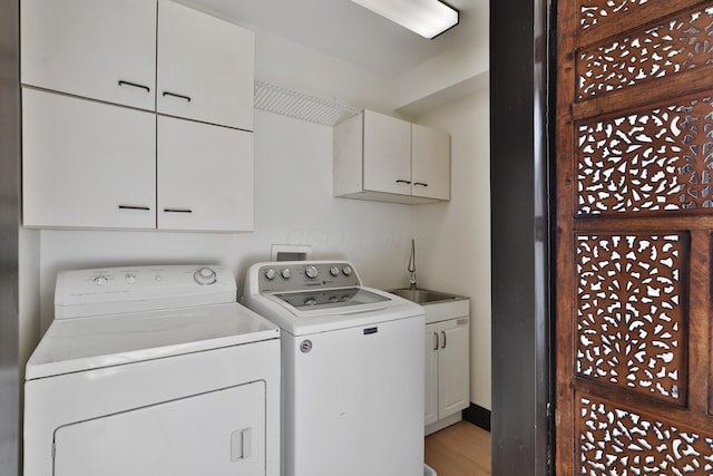 washroom with sink, light hardwood / wood-style flooring, washing machine and dryer, and cabinets