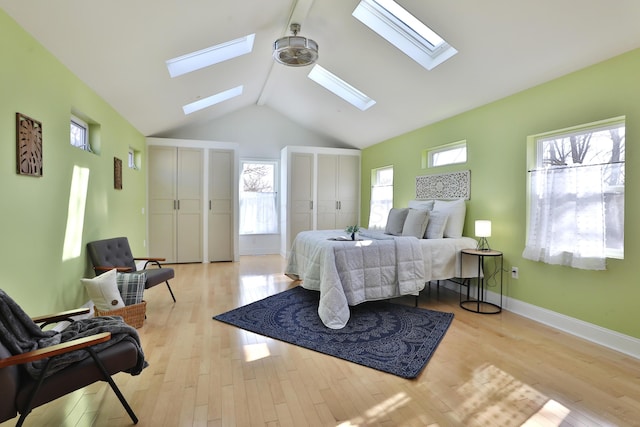 bedroom with multiple windows, vaulted ceiling, two closets, and light hardwood / wood-style floors