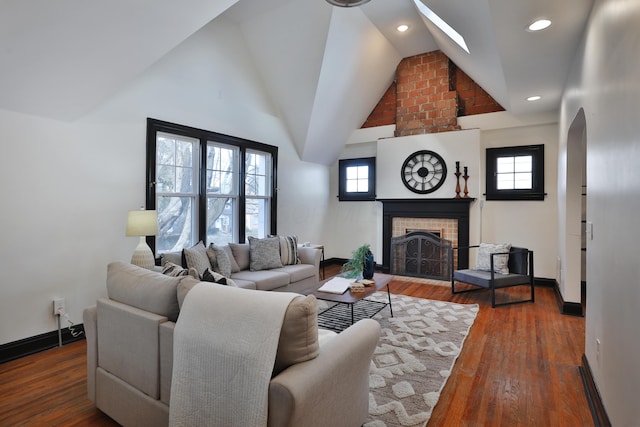 living room with a fireplace, hardwood / wood-style flooring, a wealth of natural light, and vaulted ceiling