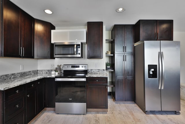 kitchen featuring dark brown cabinetry, appliances with stainless steel finishes, light stone countertops, and light wood-type flooring