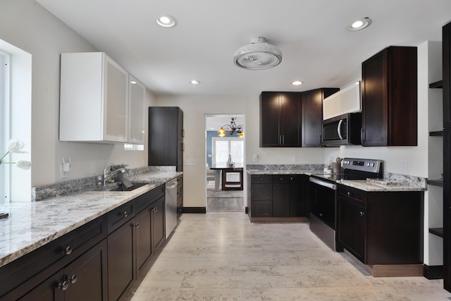 kitchen with sink, stainless steel appliances, dark brown cabinetry, light stone countertops, and light wood-type flooring