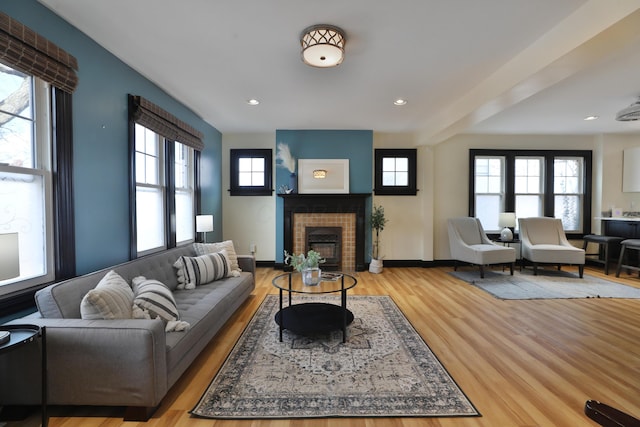 living room featuring a brick fireplace, a wealth of natural light, and light hardwood / wood-style floors