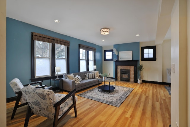 living room featuring a brick fireplace and light hardwood / wood-style flooring