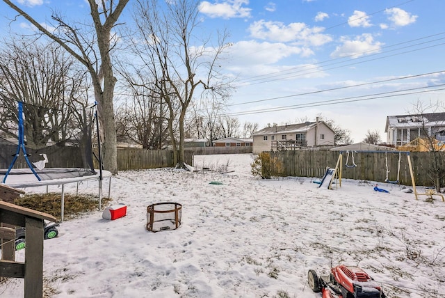 yard layered in snow featuring a playground and a trampoline