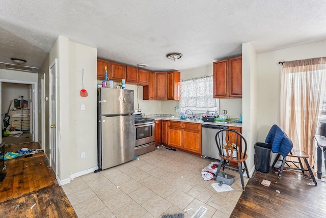 kitchen featuring stainless steel appliances, sink, and a textured ceiling