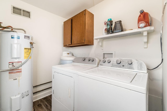 laundry area with cabinets, electric water heater, washing machine and clothes dryer, and dark hardwood / wood-style floors