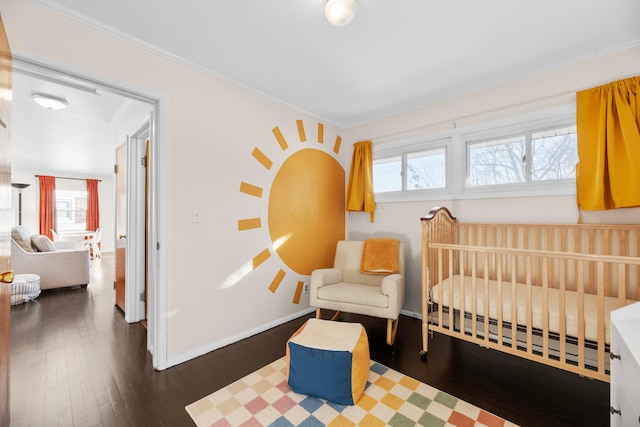 bedroom featuring a crib, crown molding, and dark hardwood / wood-style floors