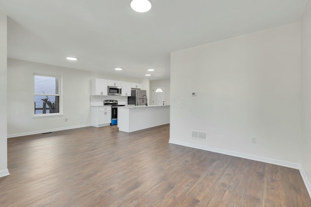 unfurnished living room featuring a healthy amount of sunlight and dark hardwood / wood-style flooring