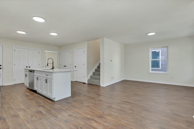 kitchen featuring sink, white cabinetry, stainless steel dishwasher, hardwood / wood-style flooring, and a kitchen island with sink