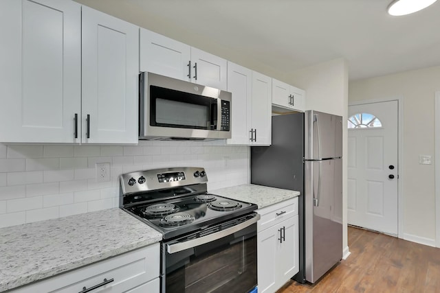 kitchen featuring light stone counters, appliances with stainless steel finishes, dark hardwood / wood-style floors, decorative backsplash, and white cabinets