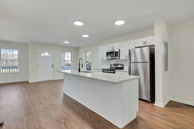 kitchen with appliances with stainless steel finishes, sink, a center island with sink, and white cabinets