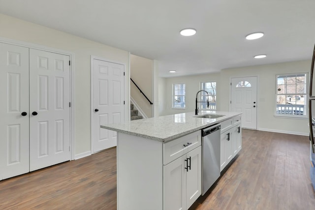 kitchen with sink, white cabinetry, a kitchen island with sink, light stone countertops, and stainless steel dishwasher