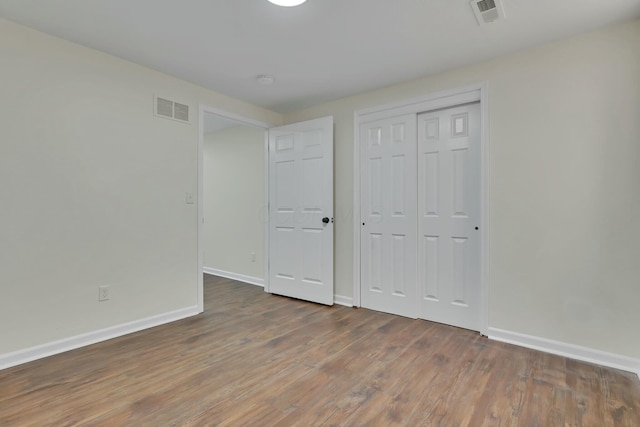 unfurnished bedroom with a closet and dark hardwood / wood-style floors