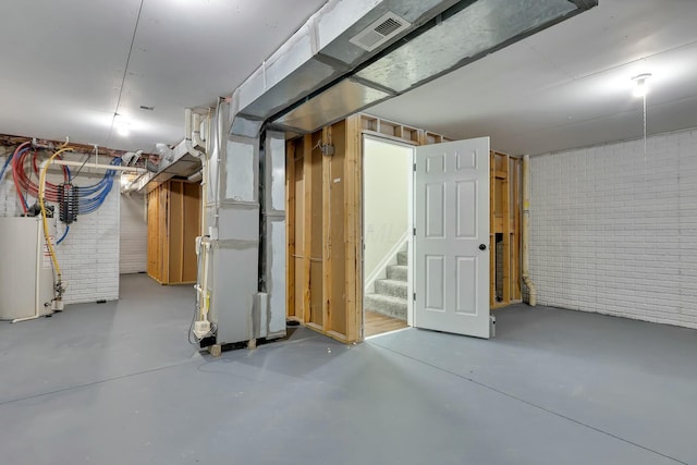 basement with water heater, brick wall, and heating unit