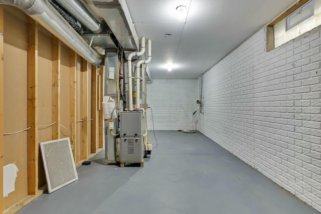 basement featuring brick wall and heating unit