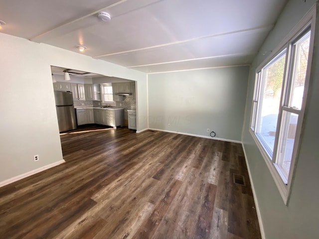 unfurnished living room with dark hardwood / wood-style floors, sink, and beam ceiling