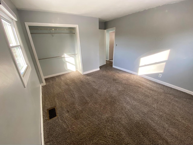 unfurnished bedroom with dark carpet and a closet