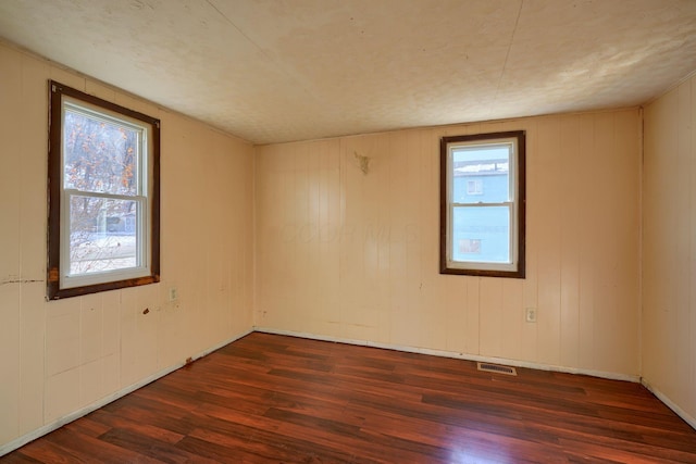 unfurnished room featuring a healthy amount of sunlight and dark hardwood / wood-style flooring