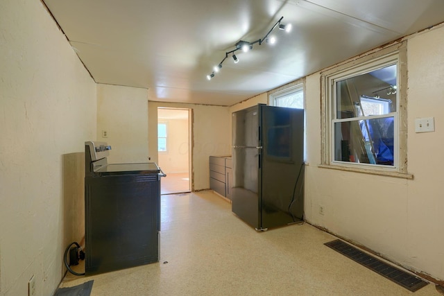 interior space with black refrigerator, track lighting, and plenty of natural light