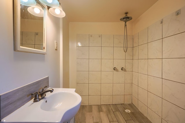 bathroom with tiled shower, wood-type flooring, and sink