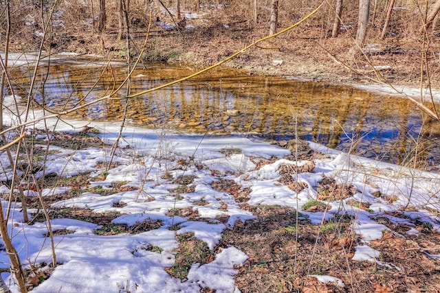 view of snow covered land with a water view