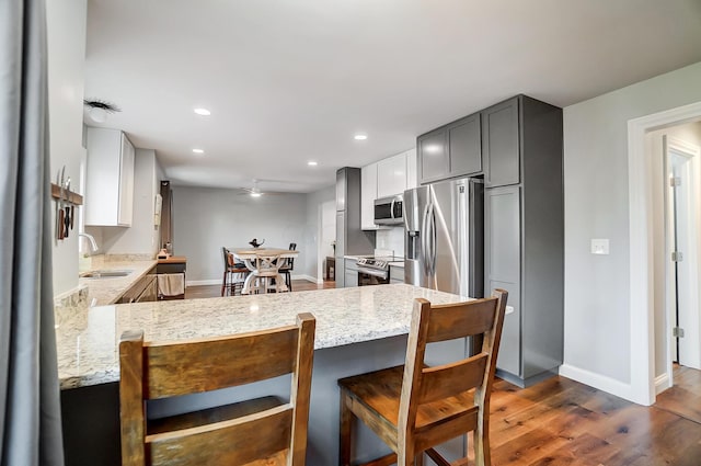 kitchen featuring sink, light stone countertops, kitchen peninsula, and stainless steel appliances