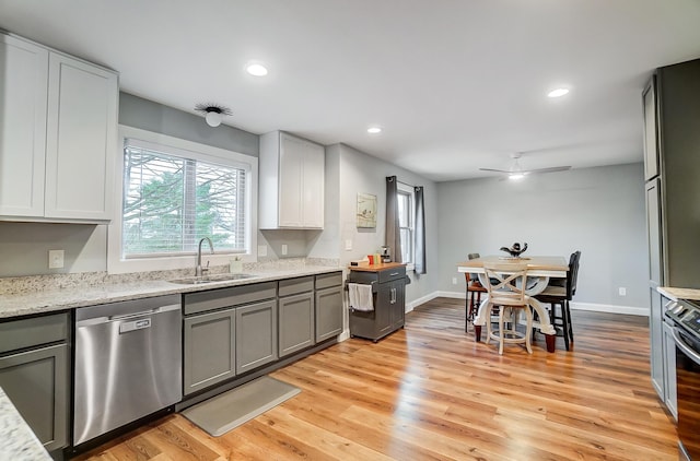 kitchen featuring stainless steel appliances, light stone countertops, sink, and light wood-type flooring