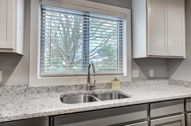 kitchen featuring sink, white cabinets, and light stone counters