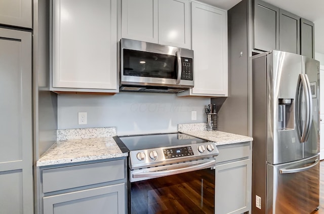 kitchen with light stone counters, appliances with stainless steel finishes, and gray cabinetry