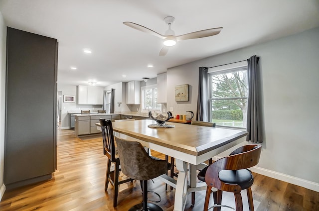 dining space featuring ceiling fan, sink, and light hardwood / wood-style flooring