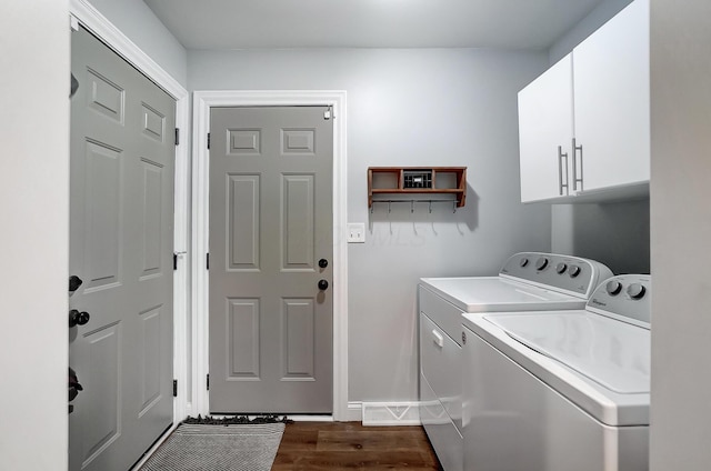 clothes washing area featuring cabinets, dark wood-type flooring, and washing machine and clothes dryer