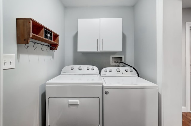 clothes washing area with cabinets, washing machine and dryer, and hardwood / wood-style flooring