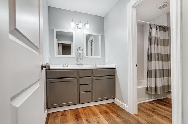 bathroom featuring hardwood / wood-style flooring, vanity, and shower / tub combo