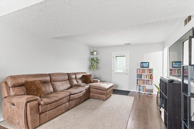 living room featuring visible vents, a textured ceiling, and wood finished floors