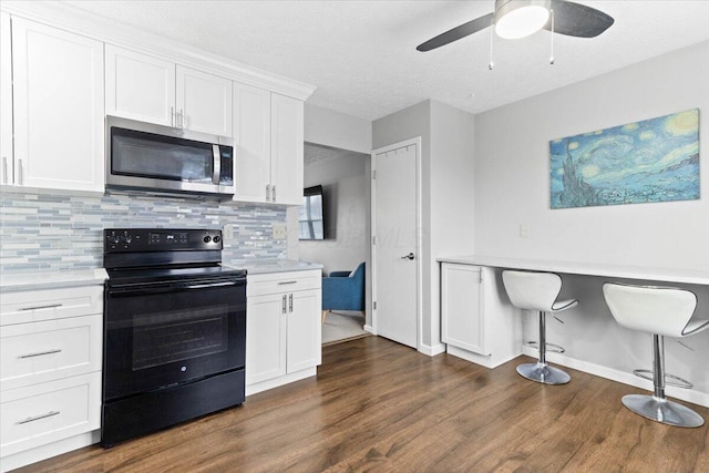 kitchen featuring stainless steel microwave, light countertops, built in desk, and black electric range