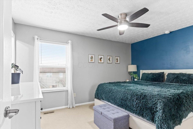 carpeted bedroom with ceiling fan, baseboards, visible vents, and a textured ceiling