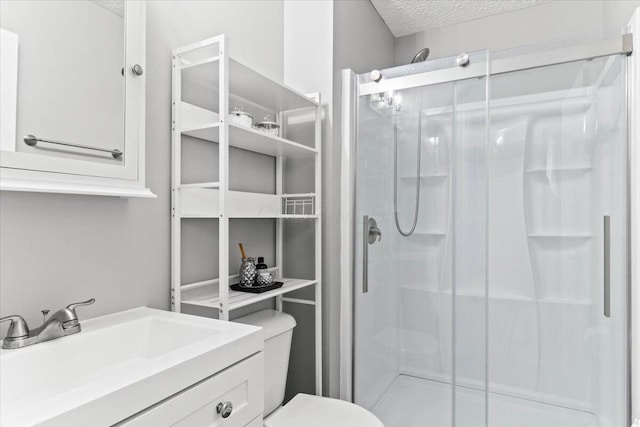 full bath with vanity, toilet, a stall shower, and a textured ceiling