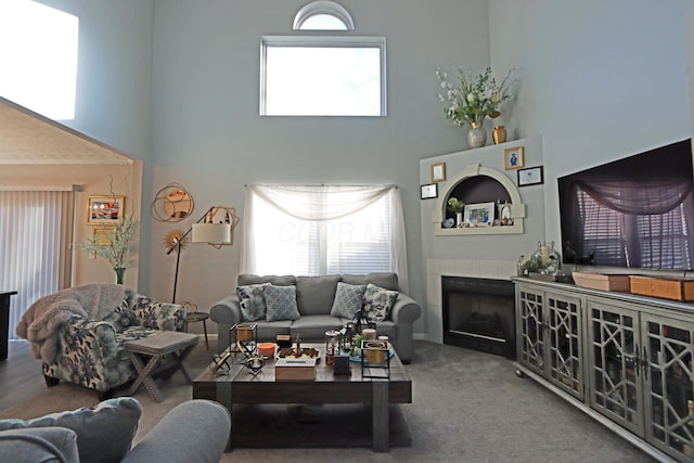 carpeted living room featuring a high ceiling and a fireplace